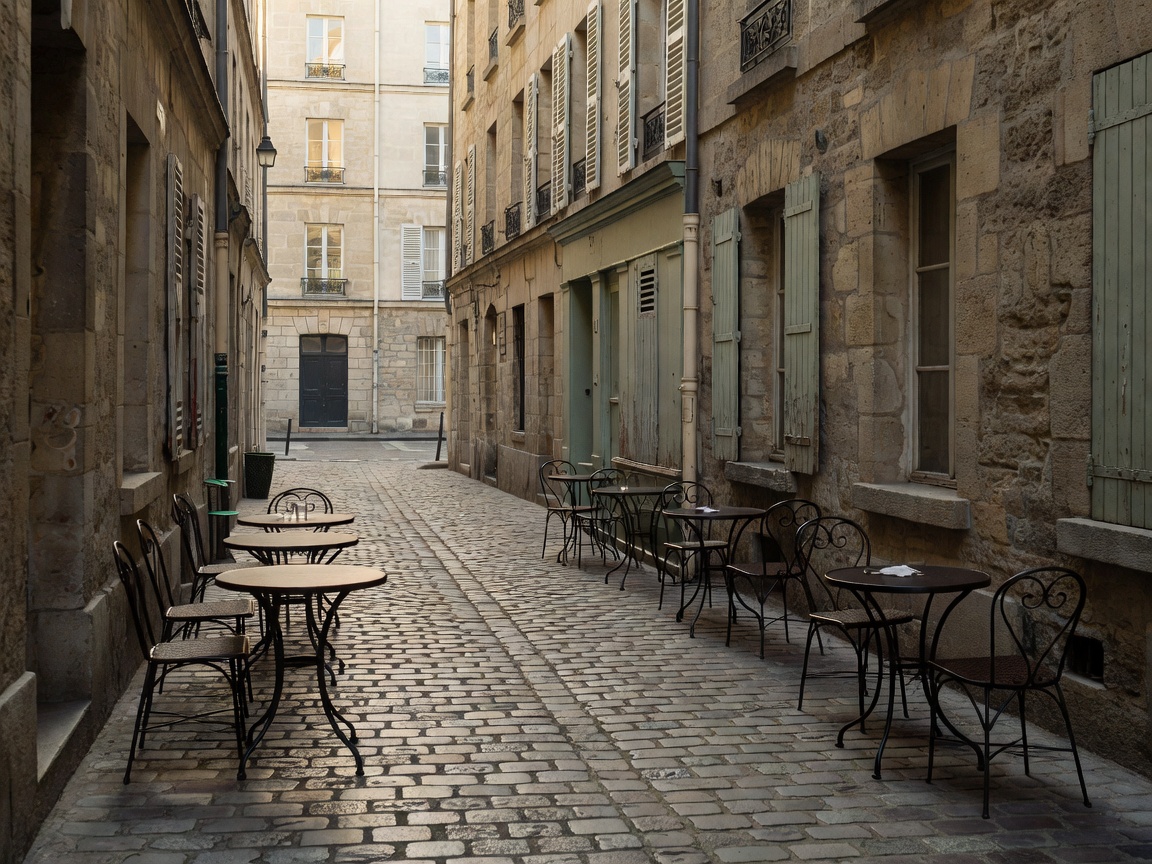 Historic cobblestone alleyway in Le Marais Paris with bistro tables